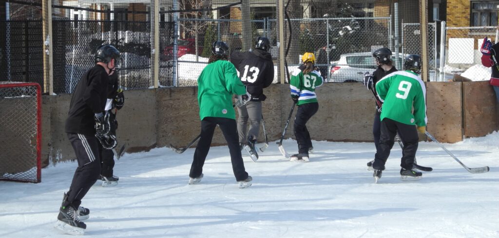 players from opposing teams hustling for puck in the corner boards