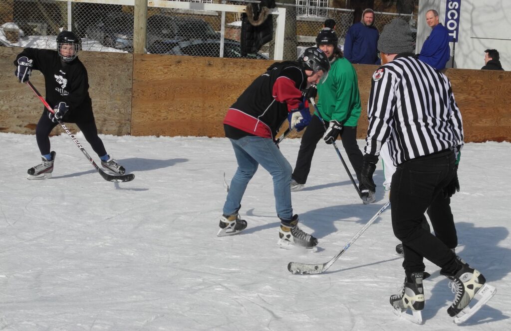 players from opposing teams skating to puck